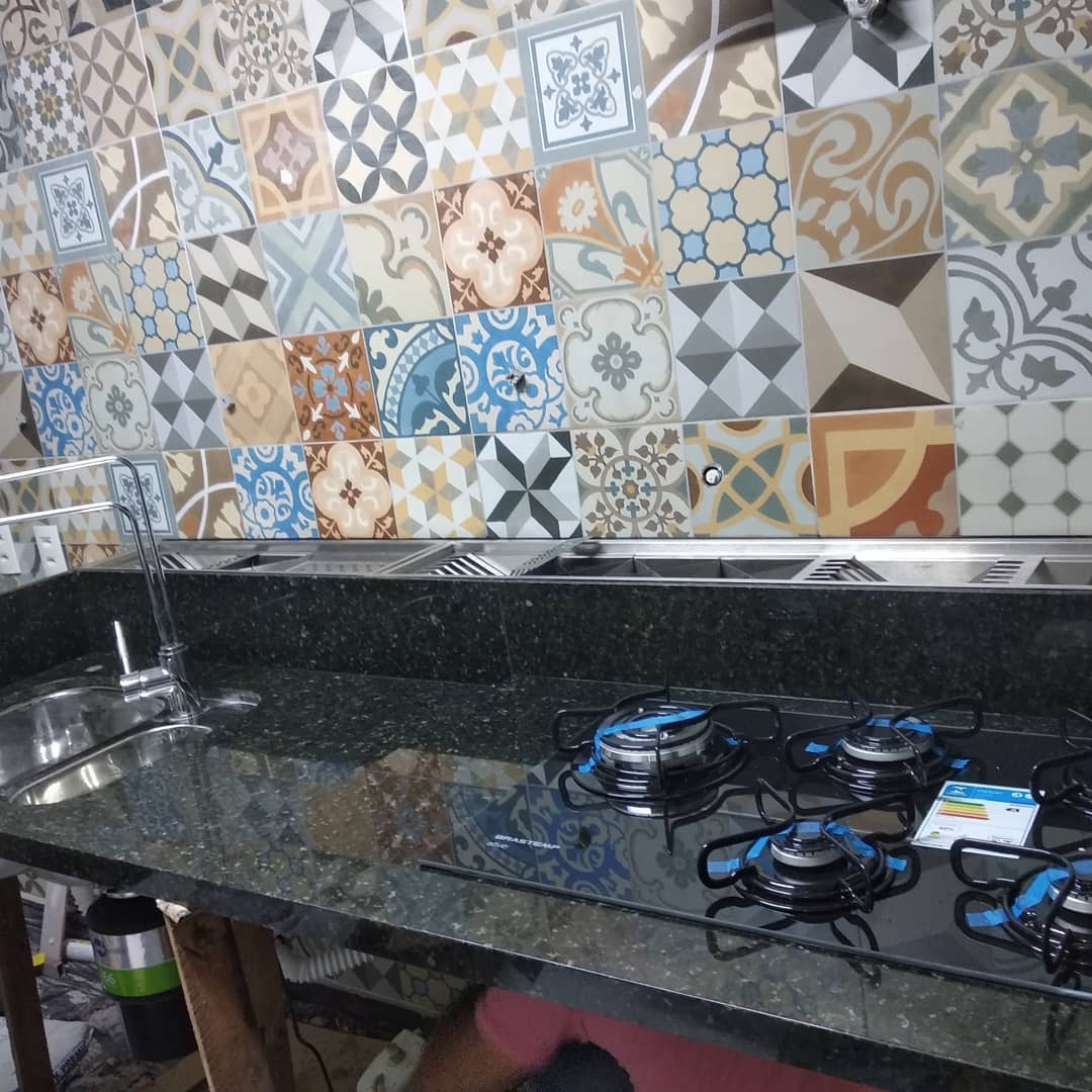 Bancada de granito escuro com cuba, cooktop e revestimento decorativo