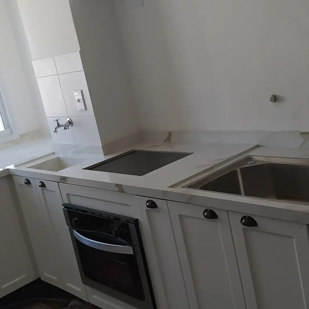 Cozinha clara com bancada sob medida, cuba e forno embutido